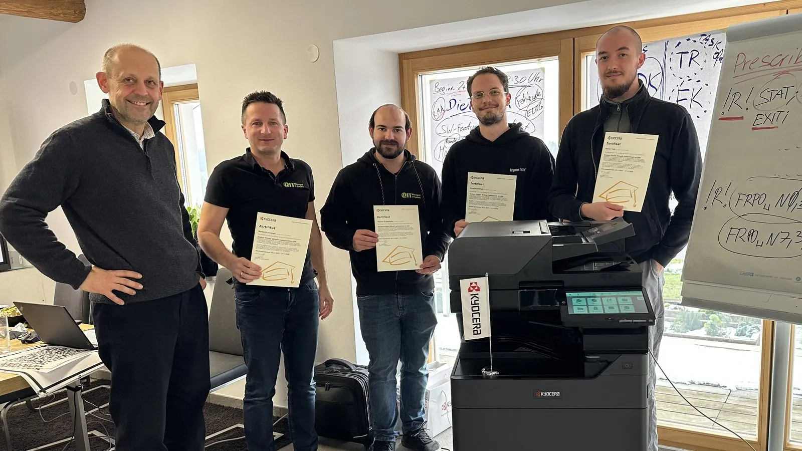 PIT-IT-Technikteam nach einer KYOCERA-Technikschulung im eigenen Haus, gemeinsam vor einem Multifunktionssystem
